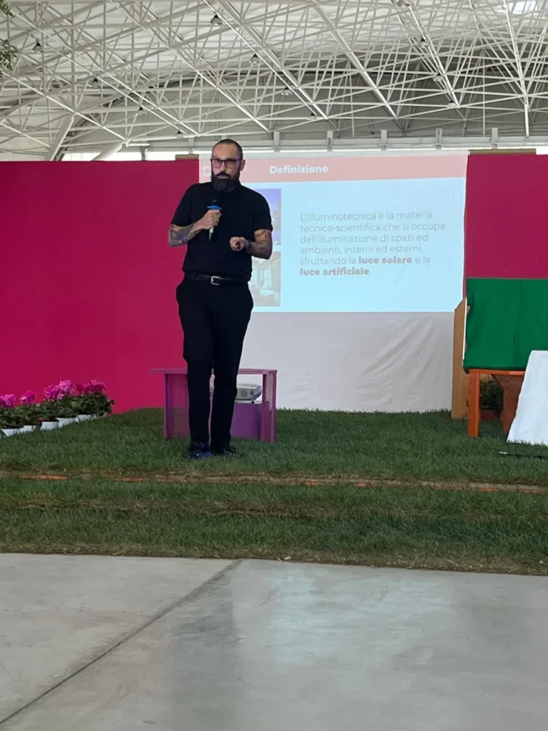Relatore al microfono durante una presentazione di illuminotecnica